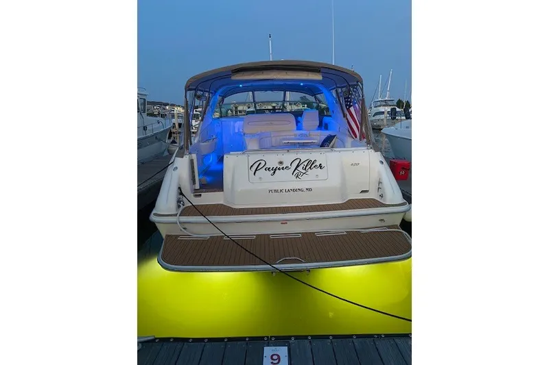 Slide: The Image of 1996 Sea Ray 450 Sundancer yacht docked with blue interior lights and American flag. - 9