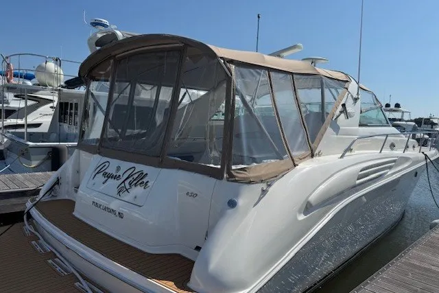 Slide: The Image of 1996 Sea Ray 450 Sundancer yacht docked, featuring a tan canopy and sleek white design. - 2