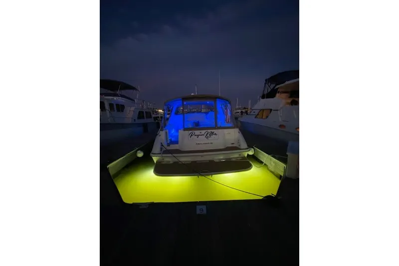 Slide: The Image of 1996 Sea Ray 450 Sundancer yacht with blue and yellow lights at night dock. - 10