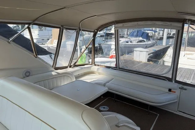 Slide: The Image of Interior view of a 1996 Sea Ray 450 Sundancer yacht with white seating and marina backdrop. - 12