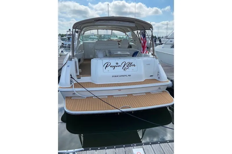 Slide: The Image of 1996 Sea Ray 450 Sundancer docked, rear view with wooden deck and American flag. - 6
