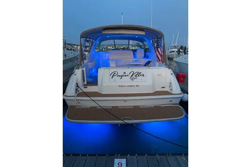 Slide: The Image of 1996 Sea Ray 450 Sundancer yacht docked, illuminated with blue lights, displaying an American flag. - 7