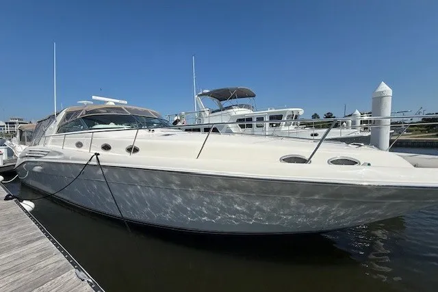 The Image of 1996 Sea Ray 450 Sundancer yacht docked at marina under clear blue sky. - 0