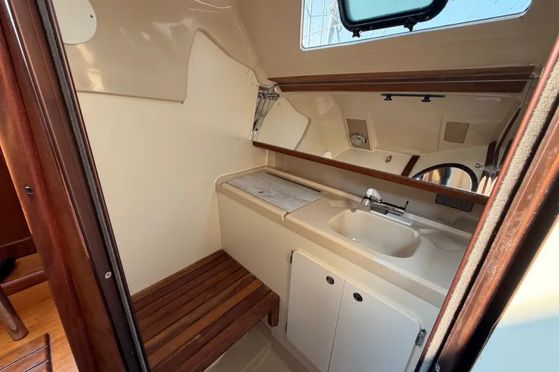 Slide: The Image of Interior of 1989 Hunter 30 sailboat bathroom with sink, mirror, and wooden bench. - 23