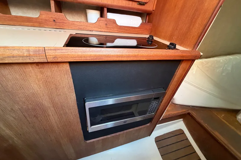 Slide: The Image of 1989 Hunter 30 yacht interior kitchen with stove and microwave, featuring wooden cabinetry. - 20