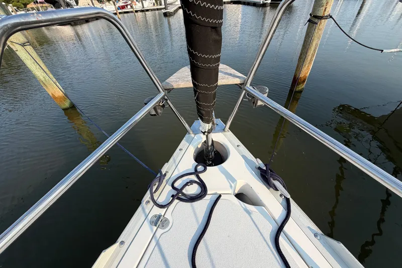 Slide: The Image of Bow of 1989 Hunter 30 sailboat docked, featuring railing and mooring lines. - 11