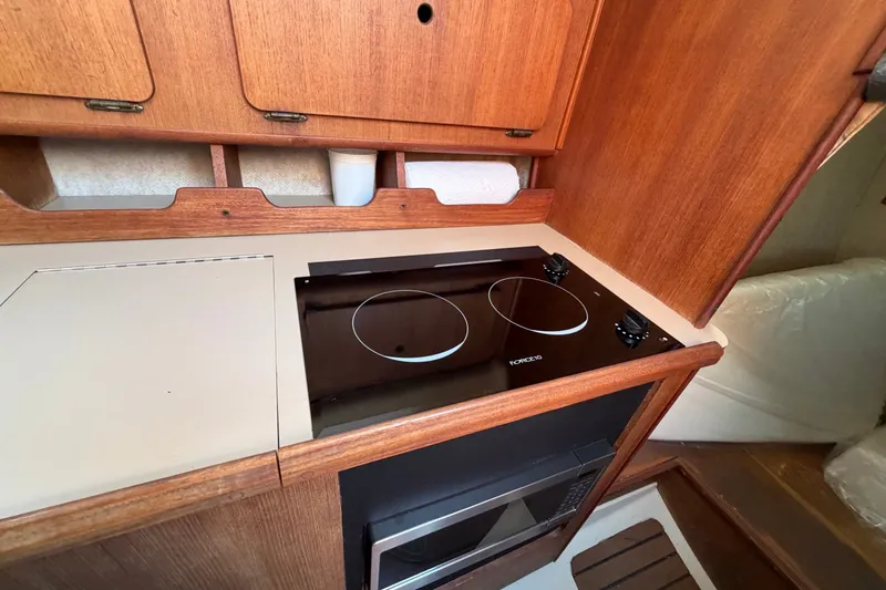 Slide: The Image of Compact kitchen area in a 1989 Hunter 30 sailboat with a modern stovetop. - 19