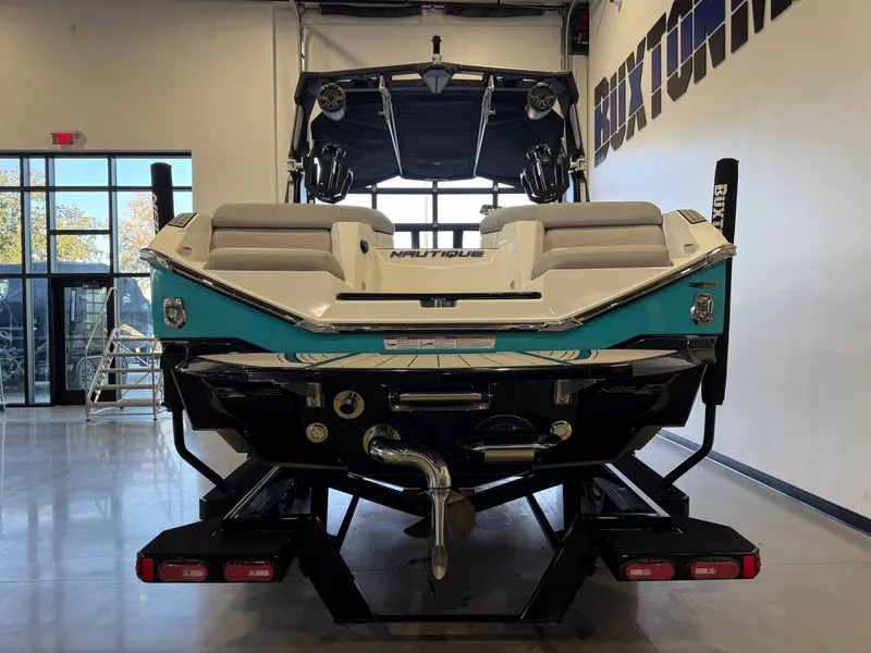 Slide: The Image of The image shows a 2024 Super Air Nautique G23 boat in a showroom on a trailer. - 7