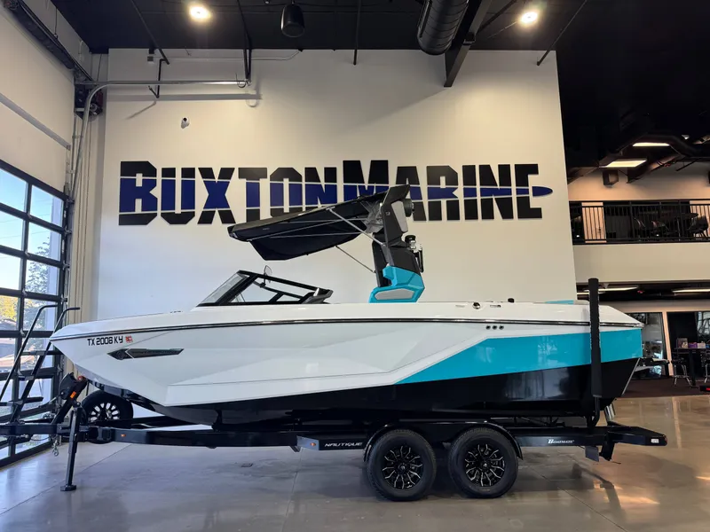 Slide: The Image of A 2024 Super Air Nautique G23 on a trailer in a showroom. The boat features a modern design with blue accents. - 4