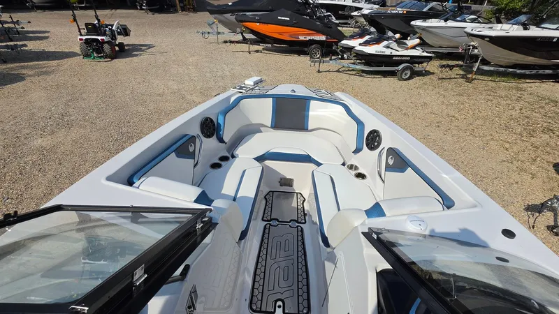 Slide: The Image of The image shows the cockpit of a 2019 Scarab 255 ID Wake Edition boat. It features white and blue upholstery. - 12