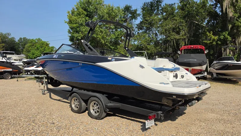 Slide: The Image of A blue and white 2019 Scarab 255 ID Wake Edition boat on a trailer in a gravel lot. - 3