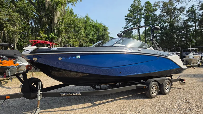 Slide: The Image of A blue 2019 Scarab 255 ID Wake Edition on a trailer outdoors. - 1