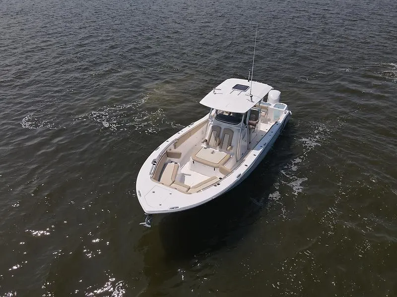 Slide: The Image of A 2018 Sea Fox 328 Commander on calm water. The boat features a spacious deck and a T-top. - 7