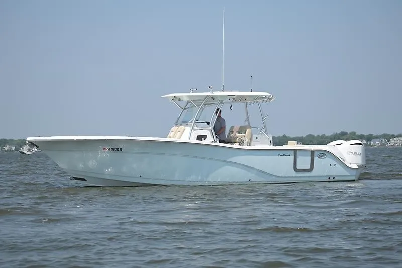 Slide: The Image of A 2018 Sea Fox 328 Commander on calm water. It features a white canopy and twin outboard engines. - 2
