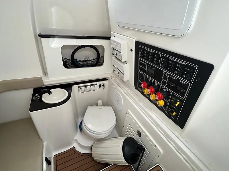 Slide: The Image of Interior view of a boat with a toilet, sink, and control panel. White and black fittings. - 16