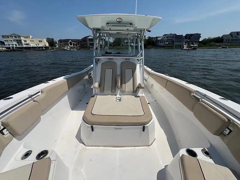 Slide: The Image of The image shows the deck of a 2018 Sea Fox 328 Commander boat. It features beige upholstery and is on calm water with houses in the background. - 17