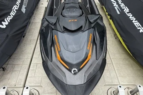 Slide: The Image of 2021 Sea-Doo GTX jet ski with sleek black and orange design on a dock. - 2