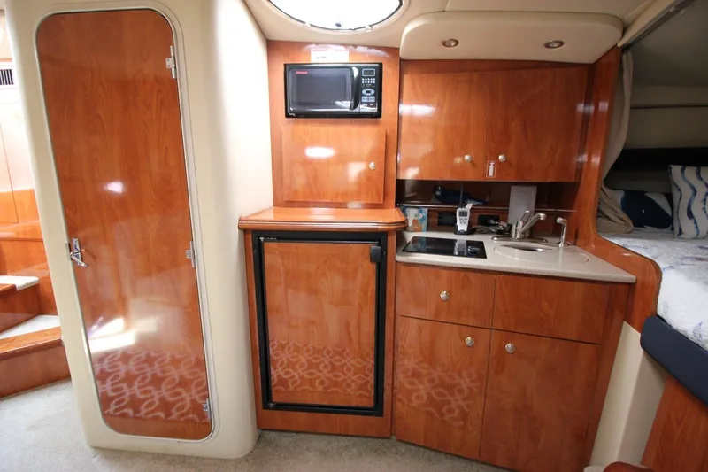 Slide: The Image of Interior of 2006 Cruisers Yachts 320 Express, featuring kitchenette with wood cabinetry and appliances. - 16