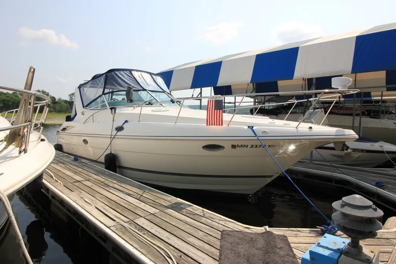 The Image of 2006 Cruisers Yachts 320 Express docked, featuring American flag and blue canopy. - 0