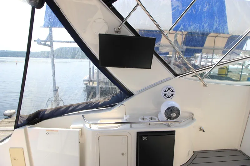 Slide: The Image of 2006 Cruisers Yachts 320 Express interior with TV, speaker, and mini fridge by the water. - 7