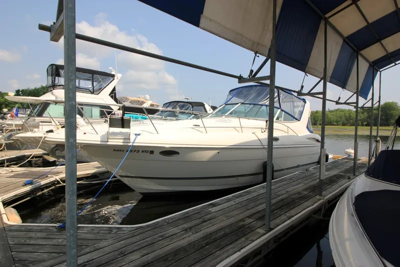 Slide: The Image of 2006 Cruisers Yachts 320 Express docked at marina under blue canopy. - 2