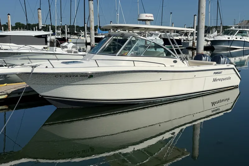 Slide: The Image of 2005 Pursuit 265 Denali LS boat docked in a marina, reflecting on calm water. - 1