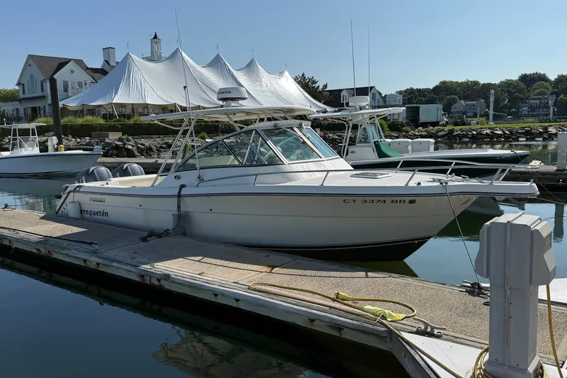 Slide: The Image of 2005 Pursuit 265 Denali LS boat docked at marina with white canopy in background. - 18