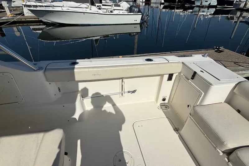 Slide: The Image of 2005 Pursuit 265 Denali LS boat interior at marina, showcasing seating and storage. - 13