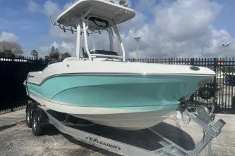 Slide: The Image of 2023 Crownline 220 CC Finseeker boat on trailer, light blue hull, parked outdoors. - 2