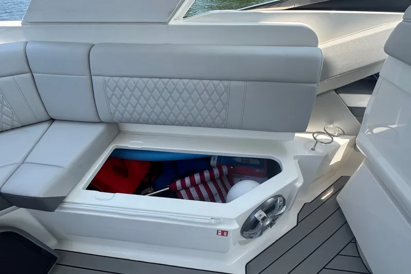 Slide: The Image of 2025 Sea Ray SLX 310 Outboard boat interior with open storage compartment and cushioned seating. - 21