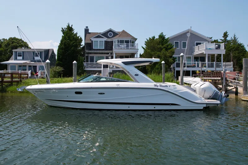 The Image of 2025 Sea Ray SLX 310 Outboard boat docked near waterfront homes. - 0