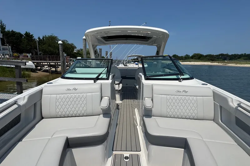 Slide: The Image of 2025 Sea Ray SLX 310 Outboard boat with luxurious seating, docked by a serene shoreline. - 47