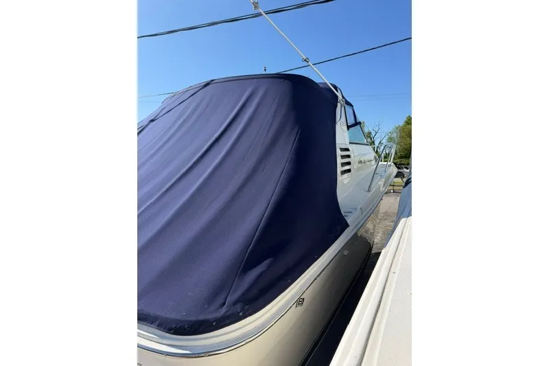 Slide: The Image of 1999 Sea Ray 330 Express Cruiser with blue cover, docked under clear sky. - 10