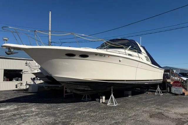 Slide: The Image of 1999 Sea Ray 330 Express Cruiser on stands, displayed outdoors under clear sky. - 1