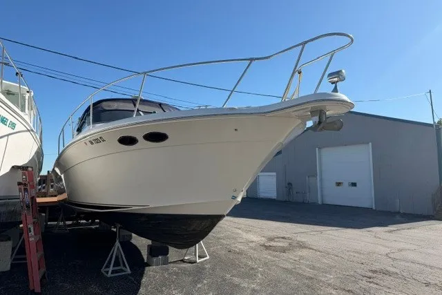 Slide: The Image of 1999 Sea Ray 330 Express Cruiser on stands, outdoor storage, clear sky background. - 2