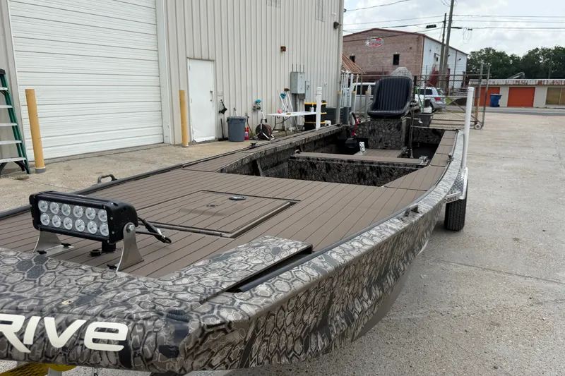 Slide: The Image of 2026 Pro-Drive 2054 X TD Stick Steer boat with camouflage design parked outside a warehouse. - 7