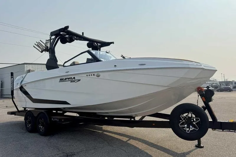 Slide: The Image of 2027 Supra SR boat on trailer, sleek white design, parked outdoors. - 4