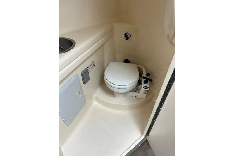 Slide: The Image of Compact bathroom in 2000 Larson Cabrio 254 boat, featuring a toilet and sink. - 7