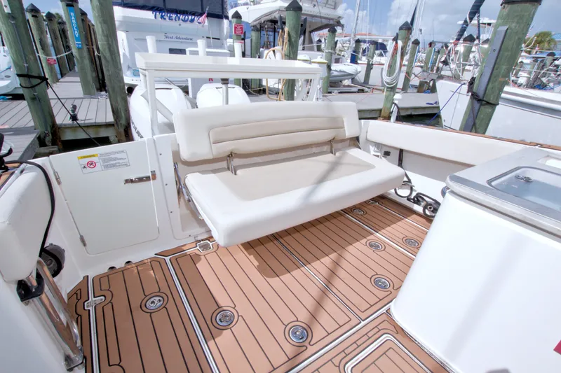 Slide: The Image of 2017 Boston Whaler 320 Vantage boat interior with foldable seating and teak flooring at a marina. - 19