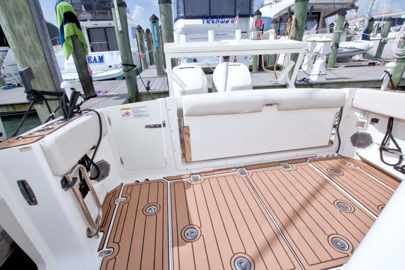 Slide: The Image of 2017 Boston Whaler 320 Vantage boat interior with teak flooring at a marina. - 18
