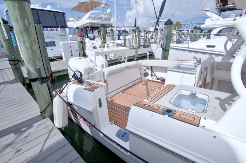 Slide: The Image of 2017 Boston Whaler 320 Vantage docked at marina, showcasing spacious deck and seating area. - 17