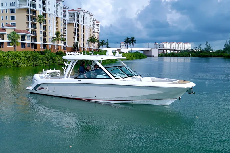 Slide: The Image of 2017 Boston Whaler 320 Vantage boat cruising near waterfront buildings under cloudy sky. - 62