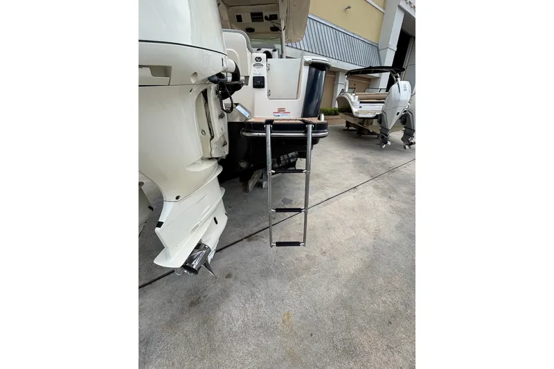 Slide: The Image of 2021 Scout 305 LXF boat with ladder and outboard motor, parked on concrete. - 15