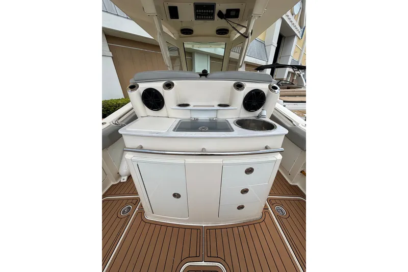 Slide: The Image of 2021 Scout 305 LXF boat interior with sink, storage, and speakers on teak flooring. - 19