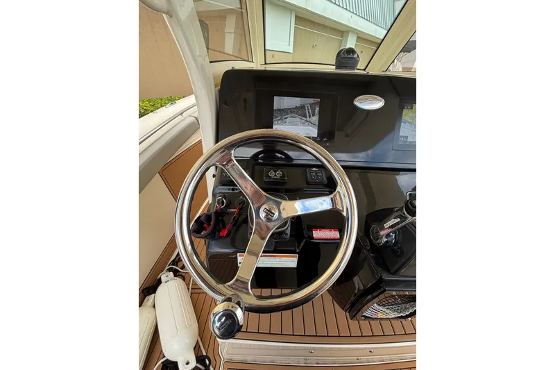 Slide: The Image of 2021 Scout 305 LXF boat helm with steering wheel and navigation display. - 35