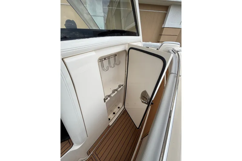 Slide: The Image of 2021 Scout 305 LXF boat interior storage compartment with open door and hooks. - 22