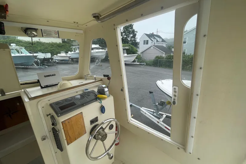 Slide: The Image of Interior view of a 1996 Rosborough Seaskiff 22 Wheelhouse Inboard, featuring steering controls and navigation equipment. - 14