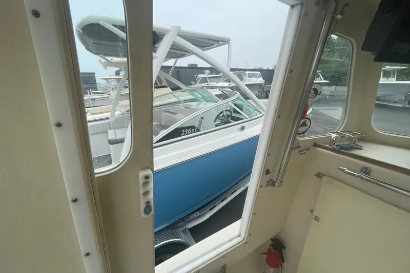 Slide: The Image of 1996 Rosborough Seaskiff 22 Wheelhouse Inboard interior view with docked boats outside. - 15