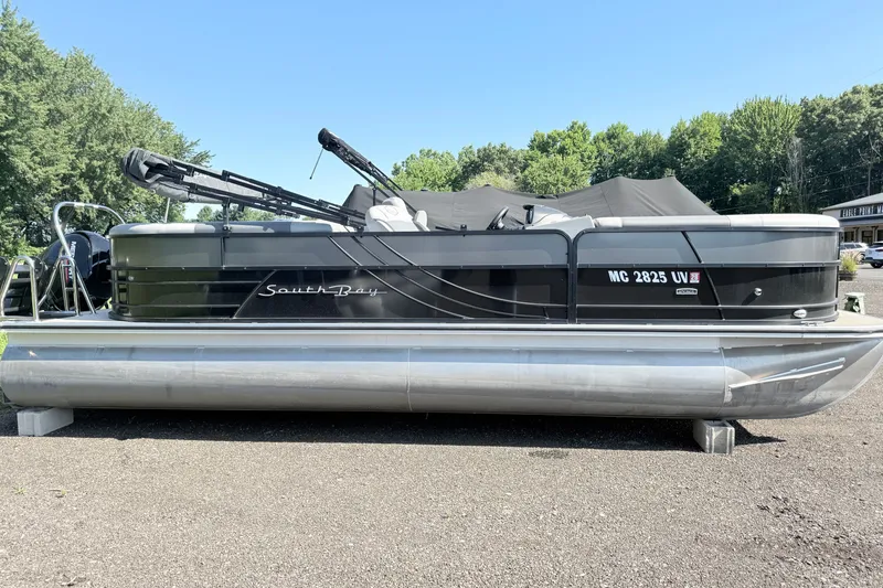 The Image of 2023 South Bay S224RS pontoon boat parked on gravel with trees in background. - 0