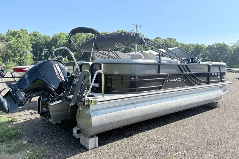 Slide: The Image of 2023 South Bay S224RS pontoon boat with Mercury outboard motor, parked outdoors. - 4
